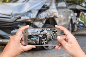 Hand of woman holding smartphone and take photo of car accident